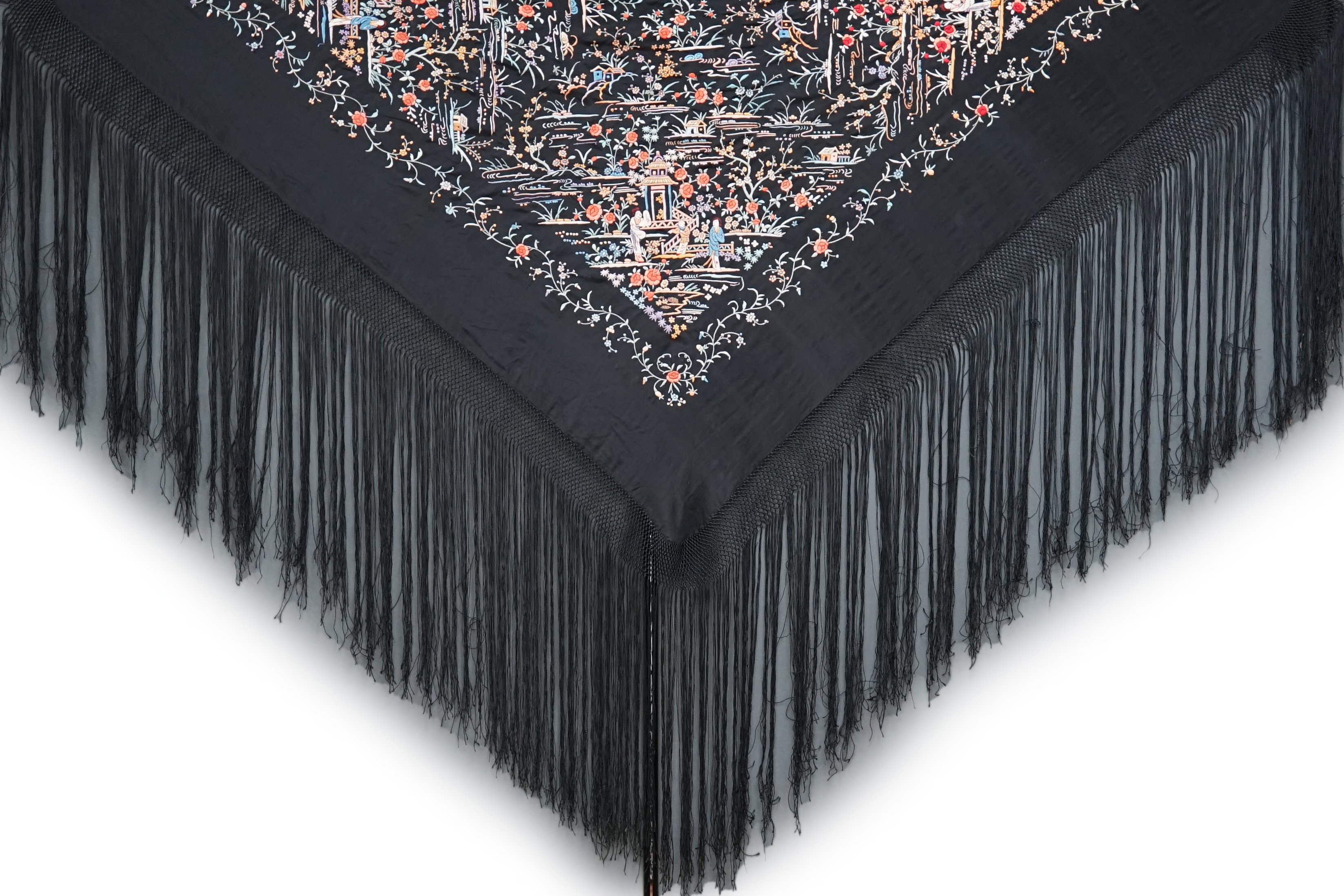 An early 20th century Chinese black silk shawl, with all over coloured floral embroidery, embroidered with multi-coloured silks and a long silk fringe, unusually the four corners are embroidered with a figurative pagoda